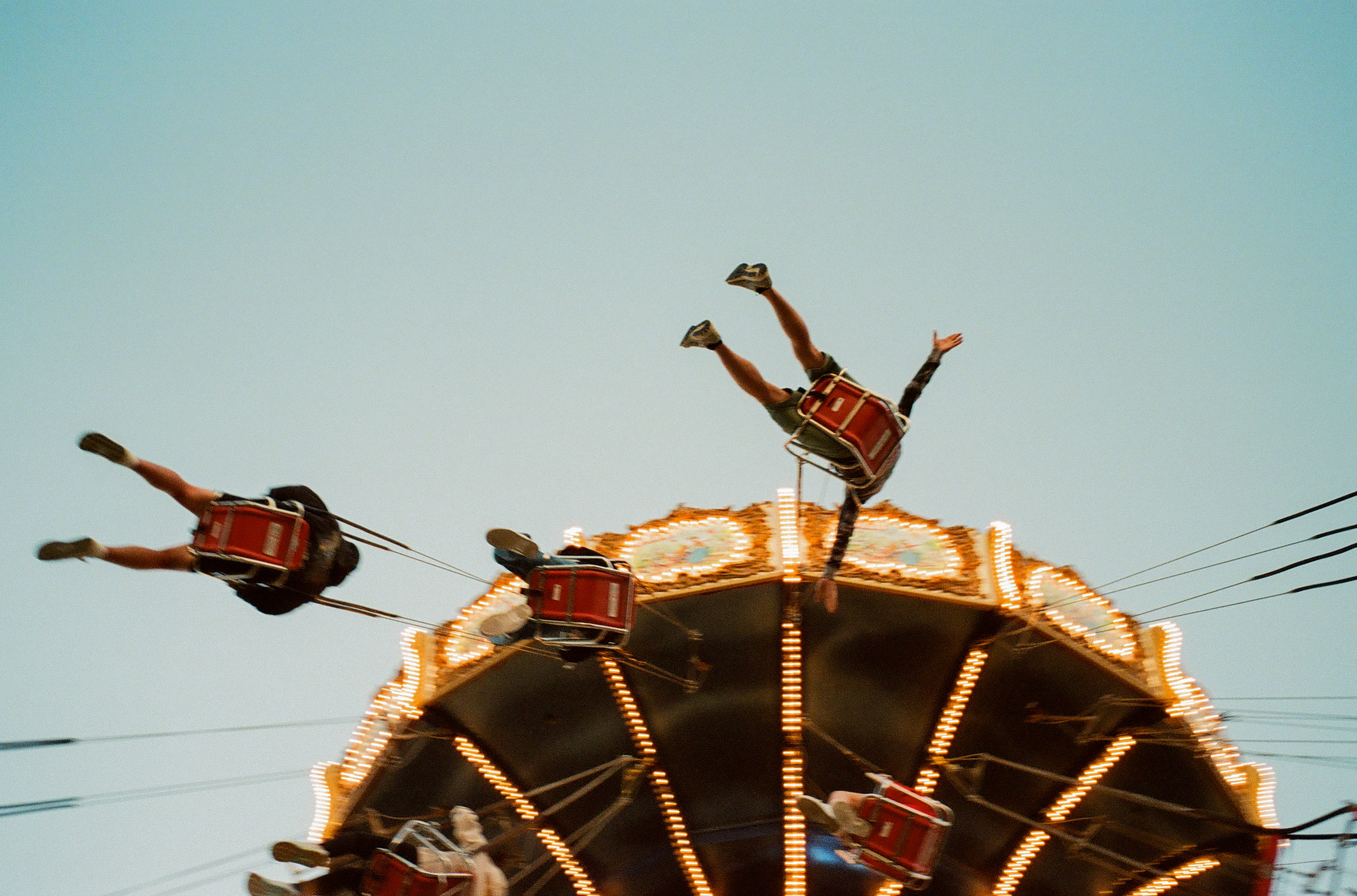 Two people fly through the air on a carnival swing ride.